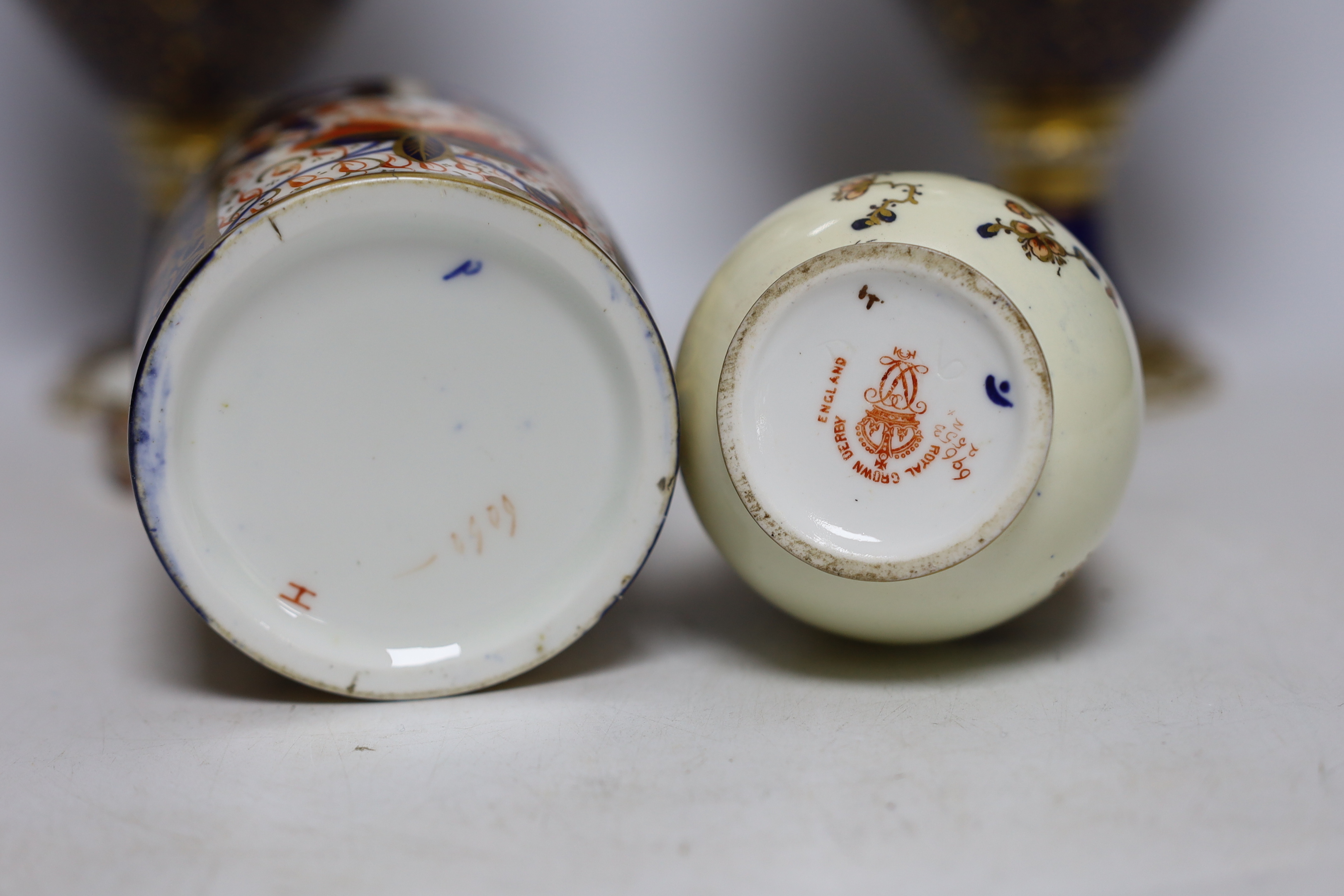 A pair of Royal Crown Derby porcelain urns and covers together with a smaller example and an Imari style jar and cover, 36cm high